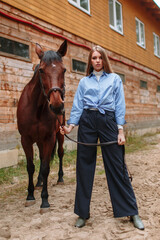 Girl rider standing next to the horse. The girl holds the horse's bridle
