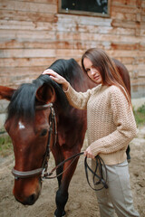 Fototapeta premium Girl rider standing next to the horse. The girl holds the horse's bridle