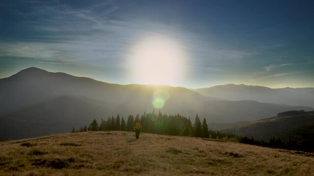 A man travels in the mountains in winter. Traveler raising arms victoriously. The concept of travel and active lifestyle. 4K