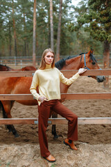 A girl standing next to a horse. Demonstration of clothing by a model