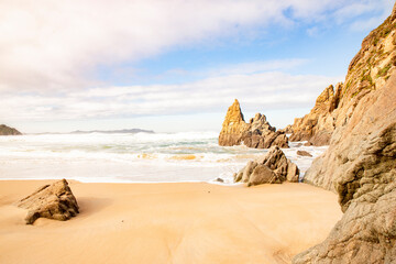 Playa rocosa en medio de un día soleado y lleno de olas