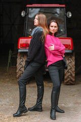 Two girls showing off their clothes against the background of a tractor