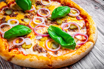 Pizza with Mozzarella cheese, Bolognese sauce, minced meat and vegetables. Italian pizza on wooden background.