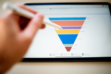 Sales marketing funnel showed on a tablet screen by a young marketer, sales manager pointing data...