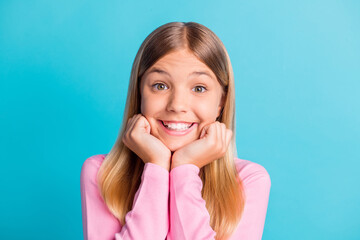 Fototapeta premium Photo portrait of cute schoolgirl with blonde hair smiling cheerfully keeping hands near face isolated on vivid turquoise color background