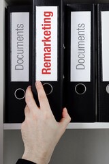 Remarketing. File Folder is taking by a hand from office shelf. Red Text is on the label of the...