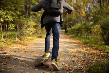 Guy in trendy clothes skateboarding in nature