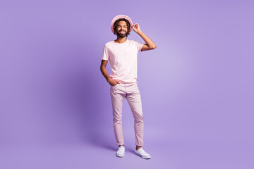 Fototapeta na wymiar Full size photo of young african handsome smiling positive man look copyspace hold hands in pockets isolated on purple color background