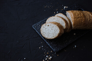 Fresh wheat sliced bread and crumbs on dark background with copy space