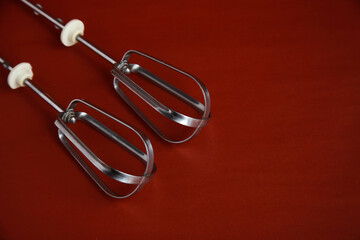 Whisks of electric mixer isolated on red background