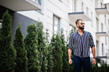 Successful arab man wear in striped shirt and sunglasses pose outdoor.