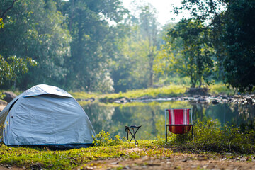 Tourism equipment. Camping tent, tourist chairs in camping by the river. A Beautiful scene in the morning.