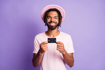Photo portrait of man holding plastic card in two hands isolated on vivid purple colored background