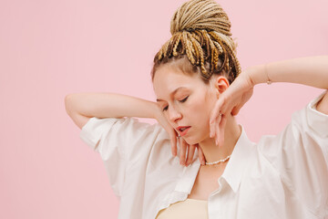 Sensual young woman with stylish blond afro braids in a bun posing over pink