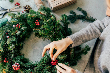 A woman is crafting a wreath for Christmas. Natural natural decoration, DIY, traditional Christmas celebration. © Ilona