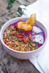Selective focus Purple smoothie bowl: Dragon fruit smoothie with banana, coconut, almonds, sunflower and chia seeds and strawberry