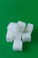Cube of white and brown sugar on a green background.