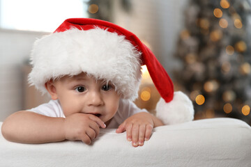 Cute little baby wearing Santa hat at home. Christmas celebration