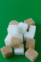 Cube of white and brown sugar on a green background.