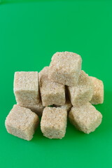 Cube of white and brown sugar on a green background.