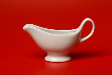 White ceramic gravy boat on a red background