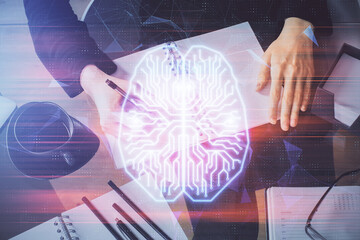 Double exposure of writing hand on background with brain hologram. Concept of learning.