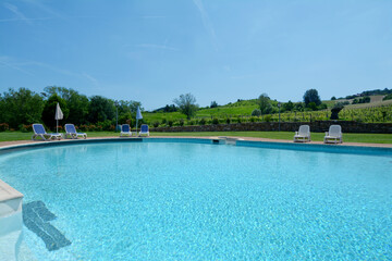 The blue and the luxury of a swimming pool in a villa between the hills and vineyards of the Langhe in Piedmont.