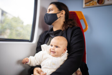 Woman looking through the window of a bus and holding her smiling baby