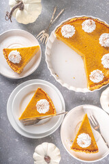 Traditional Autumn Pumpkin Pie. Homemade American Pumpkin pie topped with Whipped Cream. Rustic wooden table bakcground with Cozy plaid and sweater.