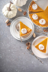 Traditional Autumn Pumpkin Pie. Homemade American Pumpkin pie topped with Whipped Cream. Rustic wooden table bakcground with Cozy plaid and sweater.