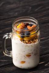 delicious granola with yogurt, nuts, peach, blueberry in glass jar