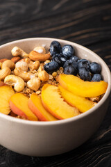delicious granola with nuts, peach, blueberry in bowl