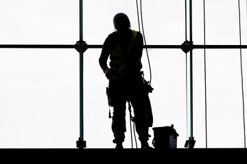 Worker silhouettes washing windows at heights