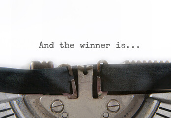 The text And the winner is..., on a white paper page inside an old vintage typewriter. Macro detail...
