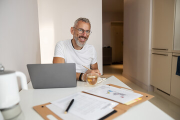 Positive male stopping doing his task and looking at camera