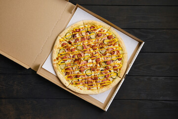 Top view of pizza with sausage, ham, pickled cucumber and mustard