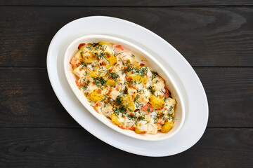 Oven-baked chicken pieces with potatoes, herbs, tomato, bell pepper and cheese
