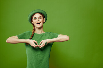 Happy woman with shamrock on St. Patrick's Day in green clothes and a hat on her head gesturing with her hands