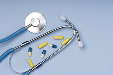 Pills And Stethoscope on blue background . Top view , copy space
