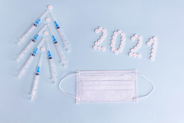 Christmas tree of syringes, medical mask and pills flat lay composition.