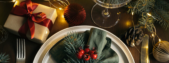 Christmas table setting with gift box on wooden table. Concept of Christmas and New Year dinner. Top view, banner for website.