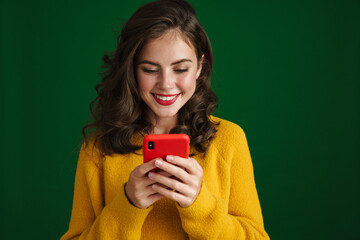 Beautiful happy brunette girl smiling and using mobile phone