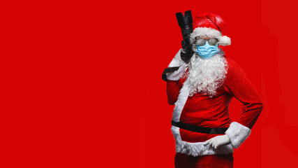 cool Santa Claus in breathing mask against corona virus taking holiday pictures - isolated on the red background