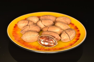 Several ripe unpeeled pecans, close-up, isolated on black.