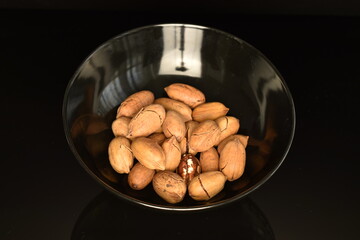 Several ripe unpeeled pecans, close-up, isolated on black.