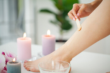 Obraz na płótnie Canvas Beautician waxing female legs in spa center