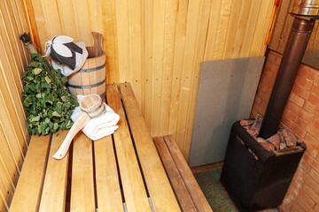 Fototapeta na wymiar Interior details Finnish sauna steam room with traditional sauna accessories basin birch broom scoop felt hat towel. Traditional old Russian bathhouse SPA Concept. Relax country village bath concept.