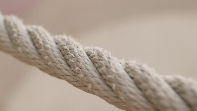Close-up of part of twisted rope. Action. Macro photography of villi of twisted rope on blurry background. White sports rope with lint