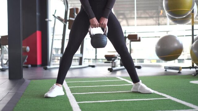 Front of woman in sportswear exercise with kettlebell at gym