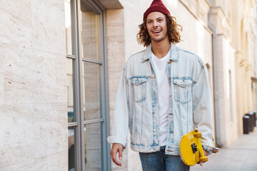 Positive young curly man with skateboard